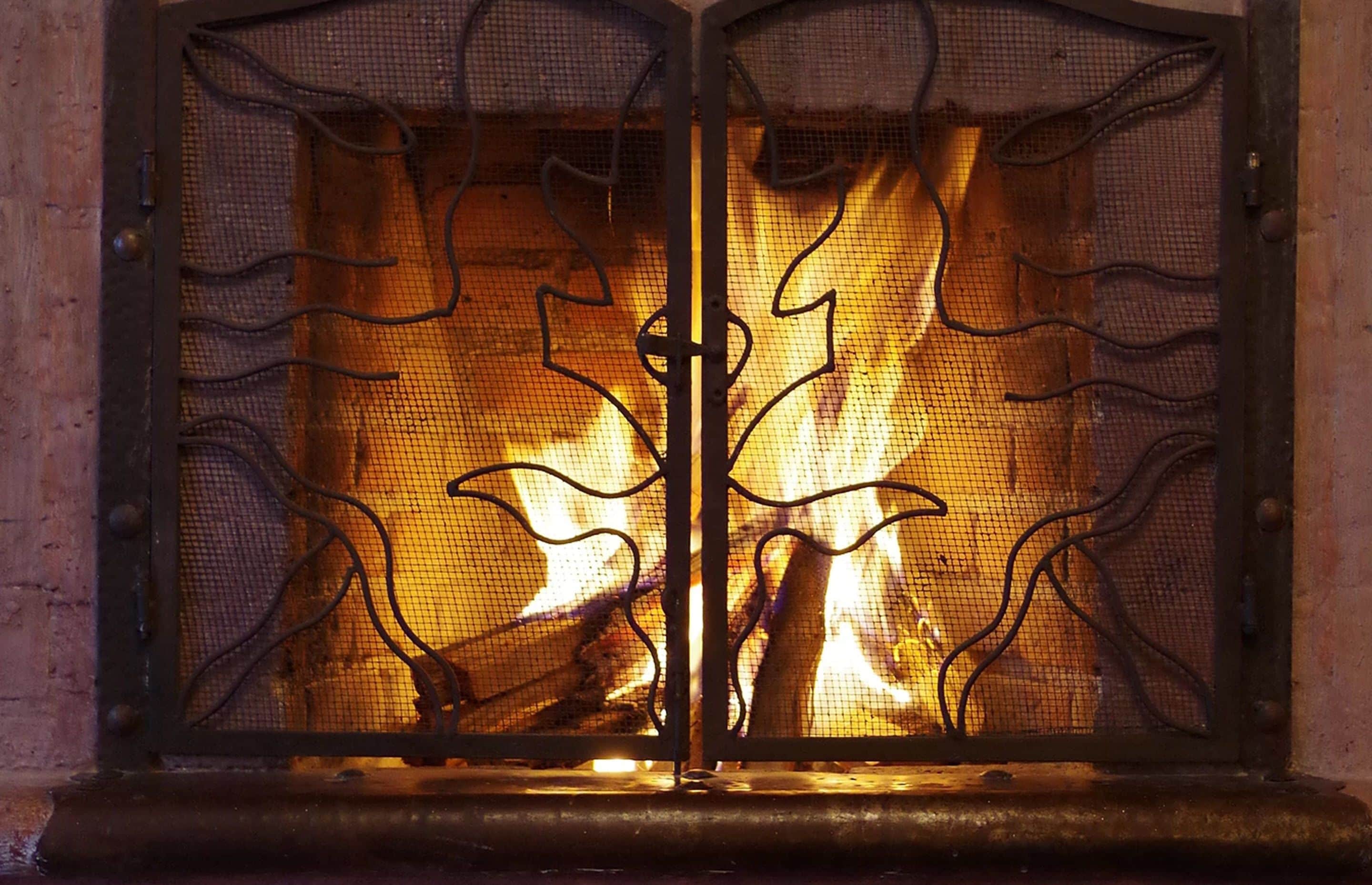 A fireplace with a metal grate and decorative metalwork.