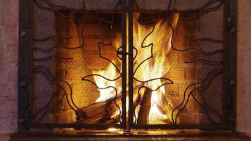 A fireplace with a metal grate and decorative metalwork.