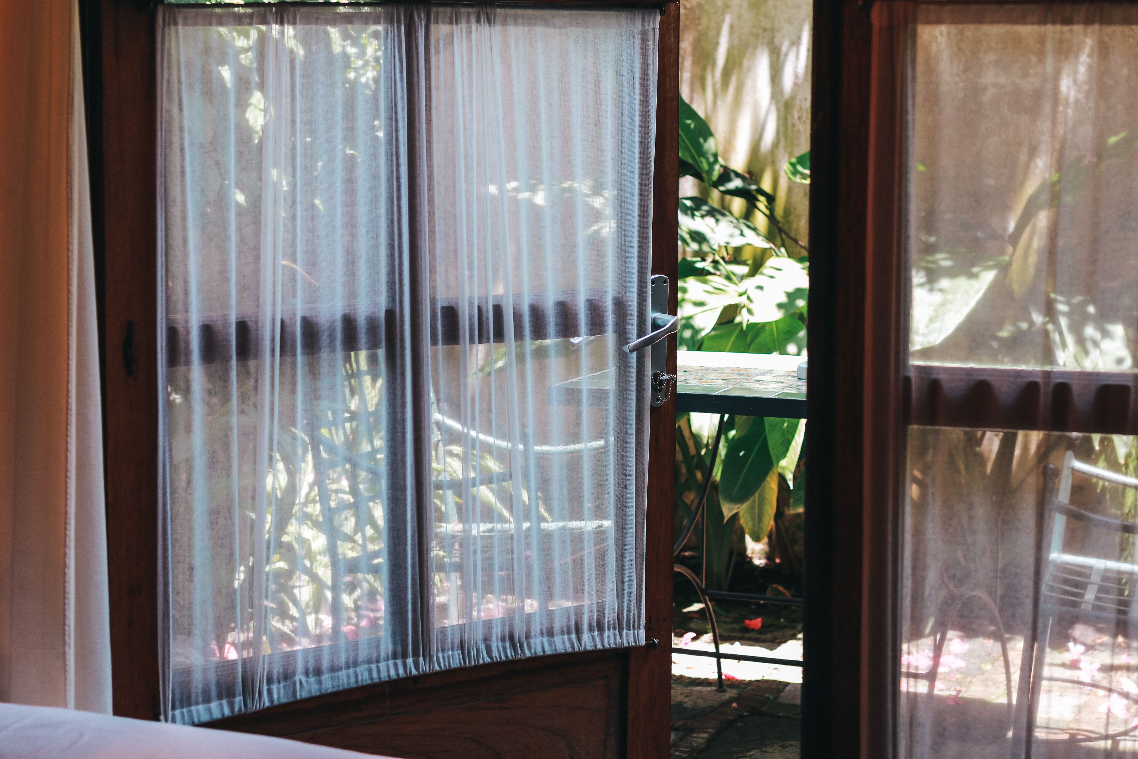 A room with a wooden door and a window with sheer curtains.