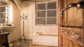 Ein Badezimmer mit Badewanne, Waschtisch mit Spiegel und einer Deckenleuchte.
