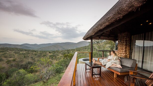 A wooden deck with a thatched roof, a sofa, and a table.