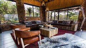 A cozy living room with a stone wall, large windows, and a red rug.