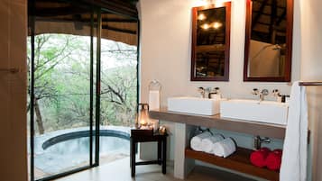 Enjoy a serene bathroom retreat with a view of the surrounding trees, featuring two sinks, a large mirror, and a convenient shelf for your essentials.