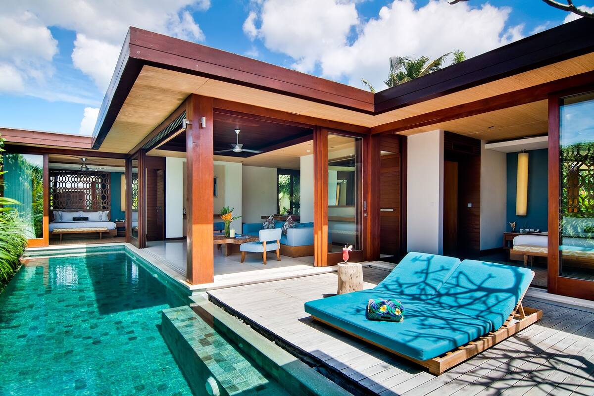 Un área de piscina exterior moderna con una silla de descanso y una terraza de madera.