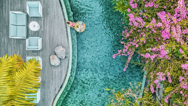 Un espace piscine aménagé sur le toit, avec une terrasse en bois, des chaises longues et un coin repas.