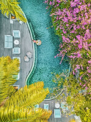 A rooftop pool area with a wooden deck, lounge chairs, and a dining setup.