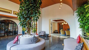 Un hall d’entrée spacieux, agrémenté d’un canapé incurvé, d’une grande plante en pot et d’un lustre moderne.