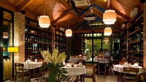 Un restaurant avec des poutres en bois, des tables blanches et des étagères remplies de bouteilles.