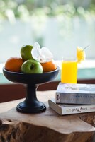 Uma mesa de madeira com uma tigela de frutas, um copo de suco de laranja e um livro chamado "American Table".