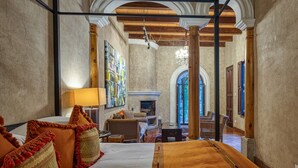 A spacious room with a large bed, a fireplace, and a view of a courtyard. - San Rafael Hotel (Antigua Guatemala)