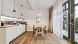 Een moderne keuken met witte kastjes, een houten aanrecht en hanglampen.