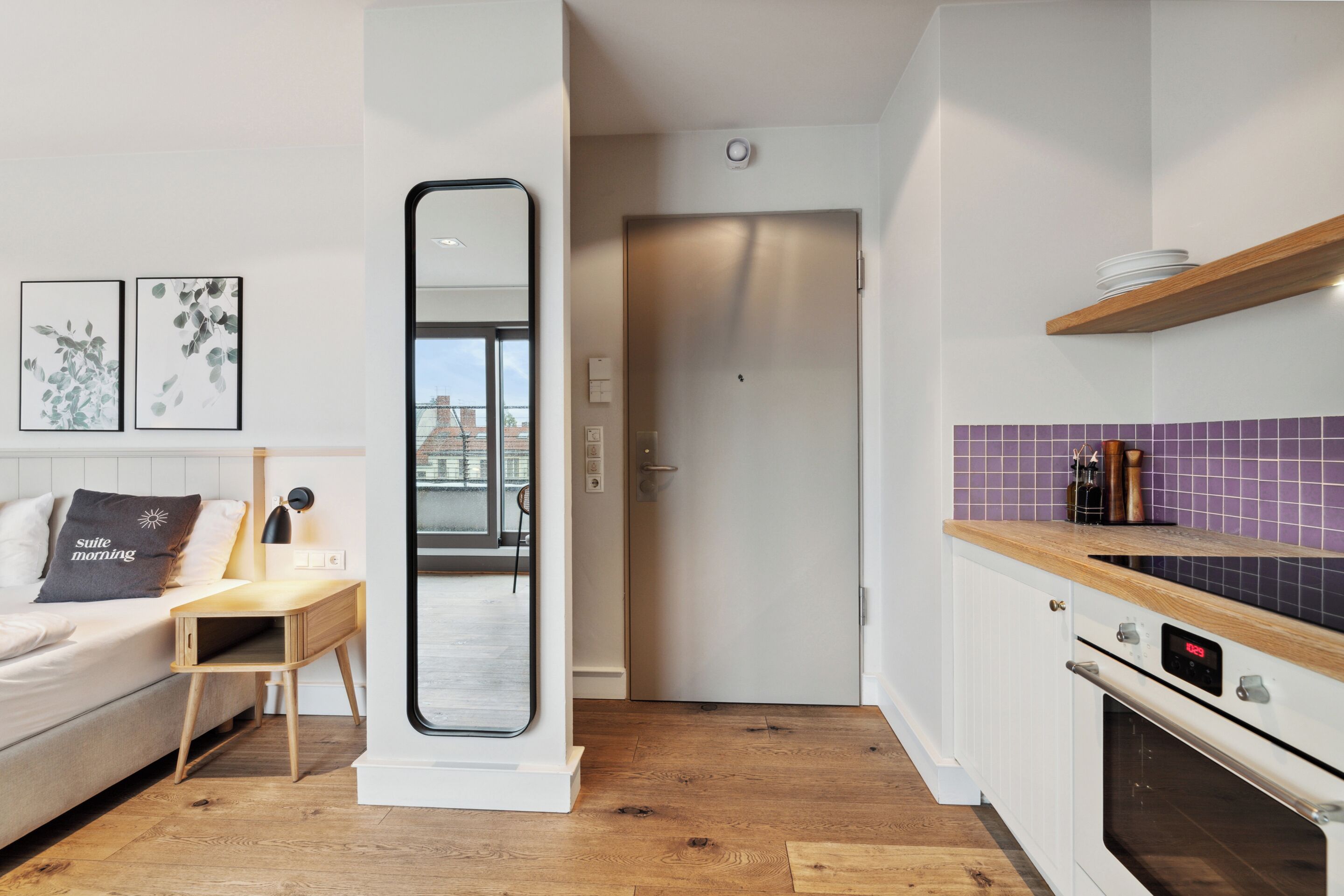 A modern kitchen with a wooden countertop, a built-in oven, and a purple-tiled backsplash.