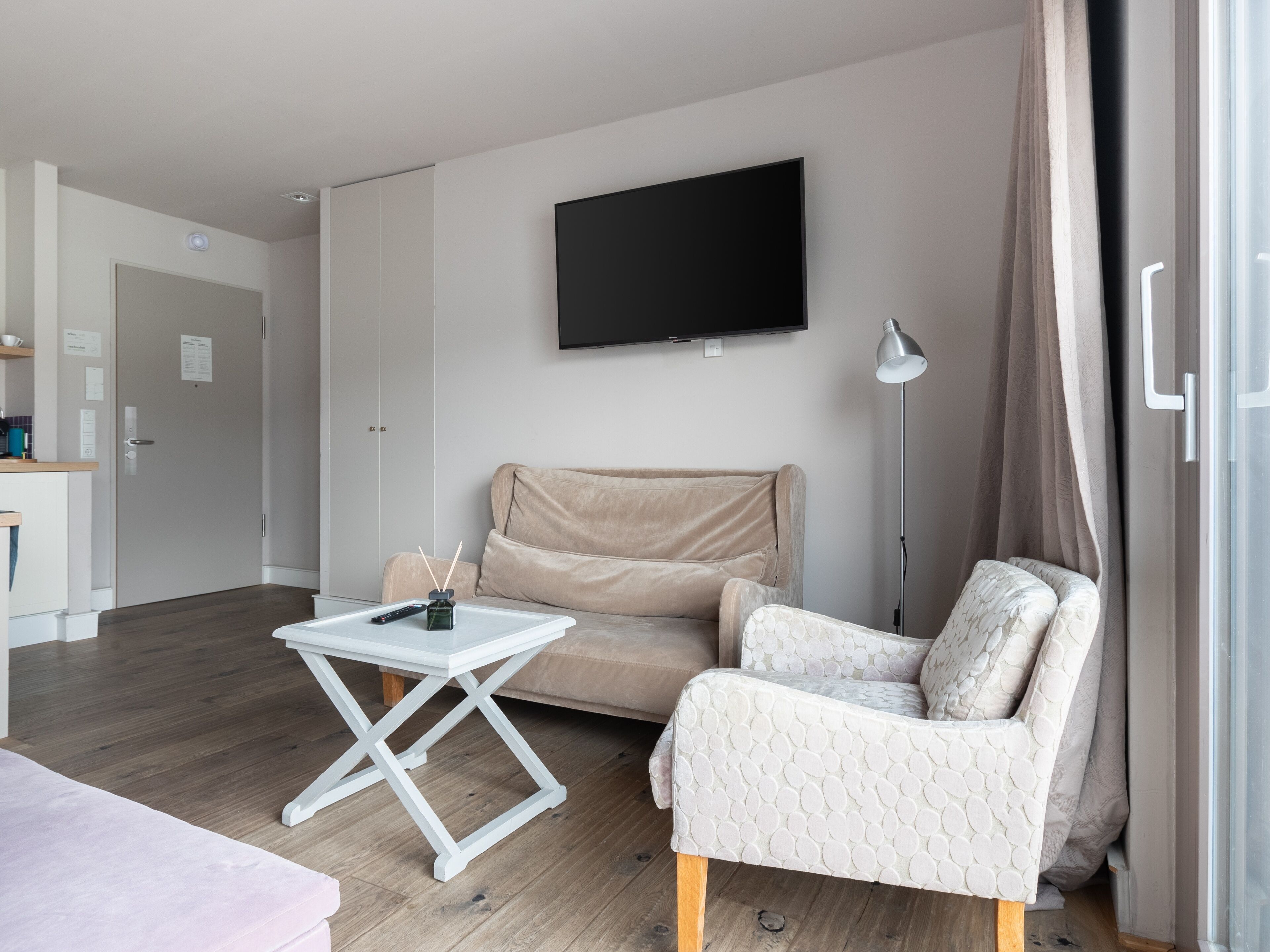 Ein modernes Wohnzimmer mit einer Couch, einem Couchtisch, einem an der Wand befestigten Fernseher und einer Stehlampe.