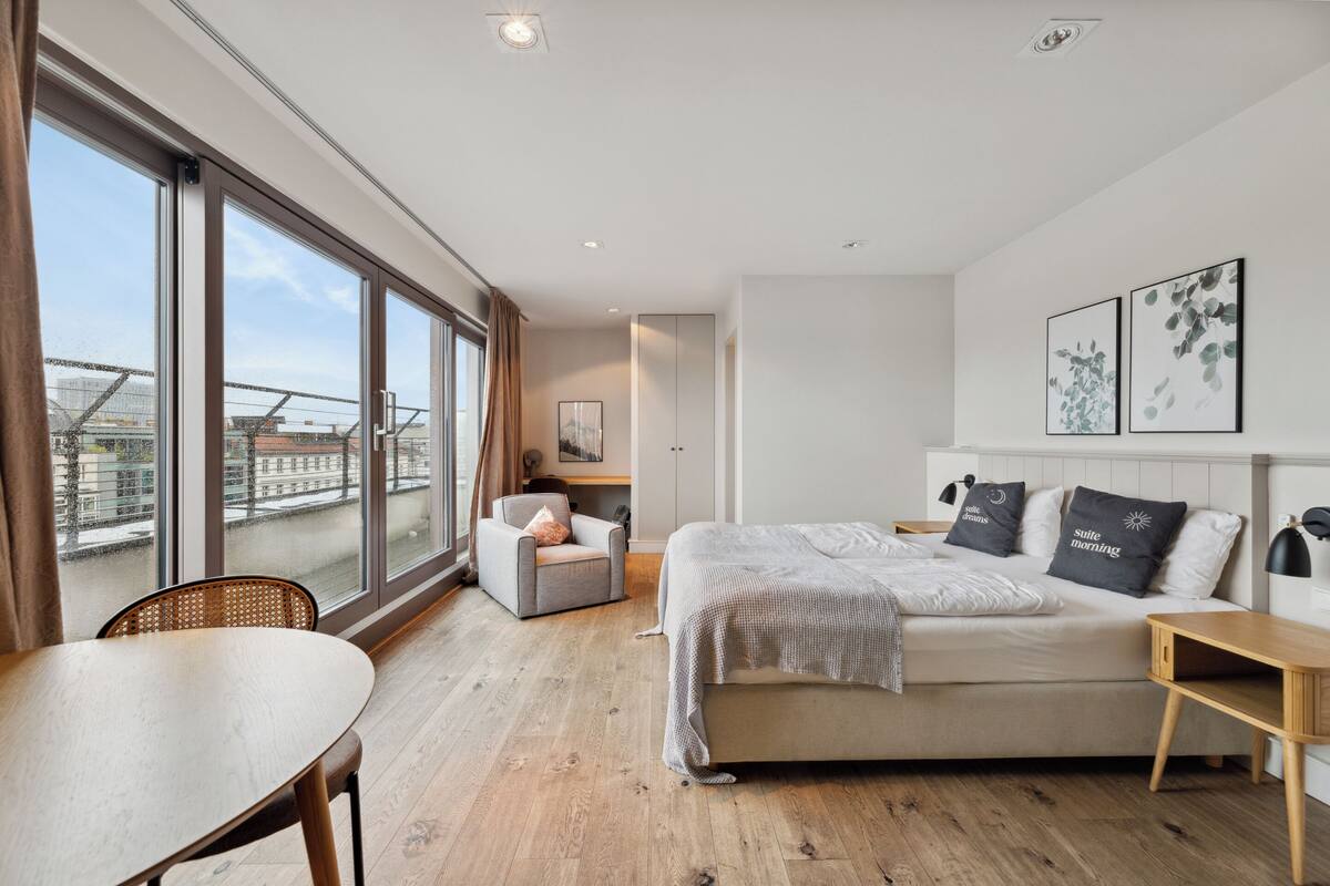 Une chambre à coucher moderne avec une grande fenêtre, un lit, une chaise et une table.
