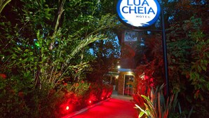 A pathway leading to the entrance of the Lua Cheia Hotel, surrounded by lush greenery and illuminated by red lights. - Pousada Lua Cheia (Marechal Deodoro)