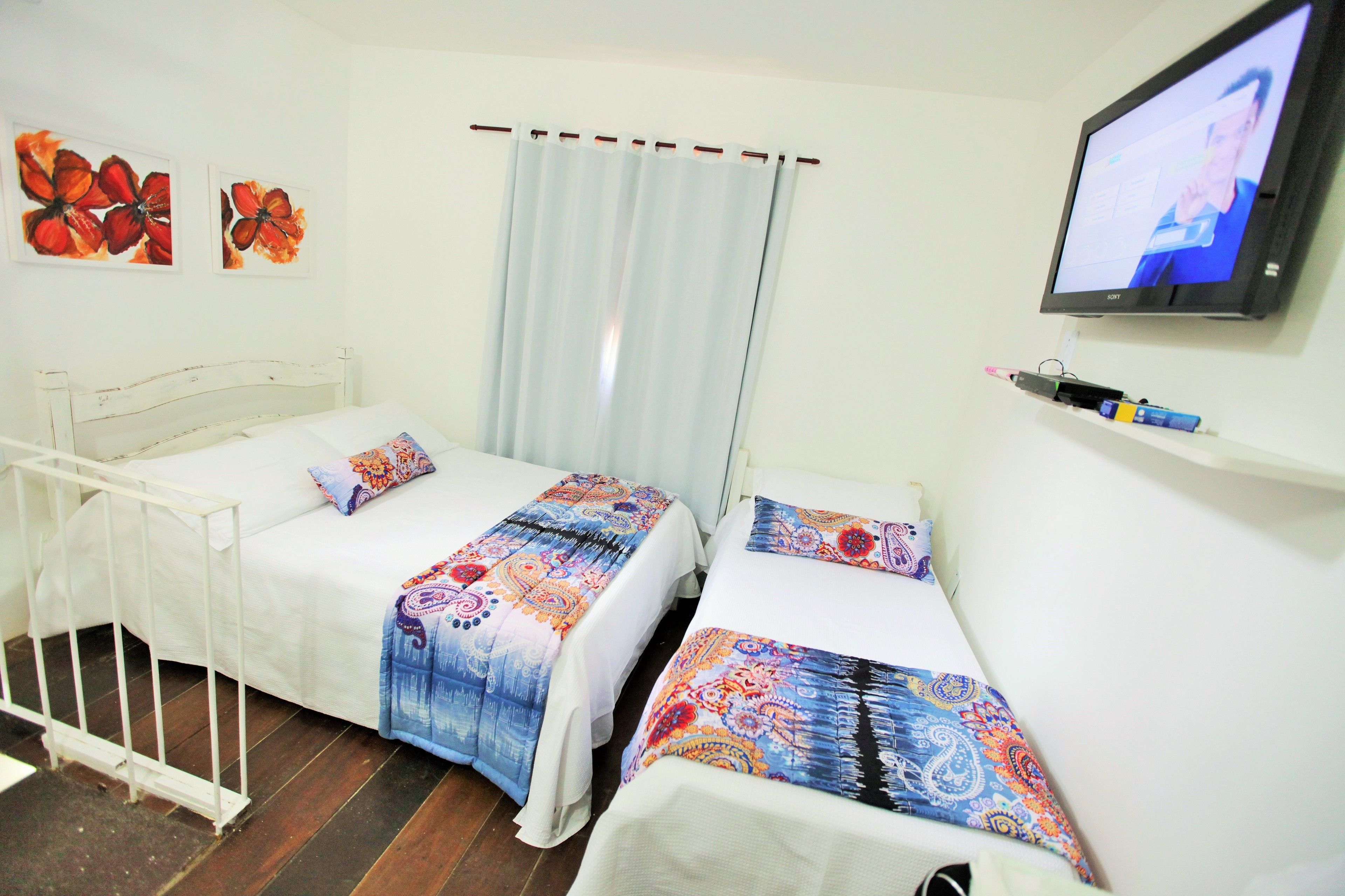 Un dormitorio con dos camas, un televisor y una cortina.