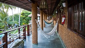 A covered outdoor area with a hammock, brick columns, and a wooden railing. - Pousada Lua Cheia (Marechal Deodoro)