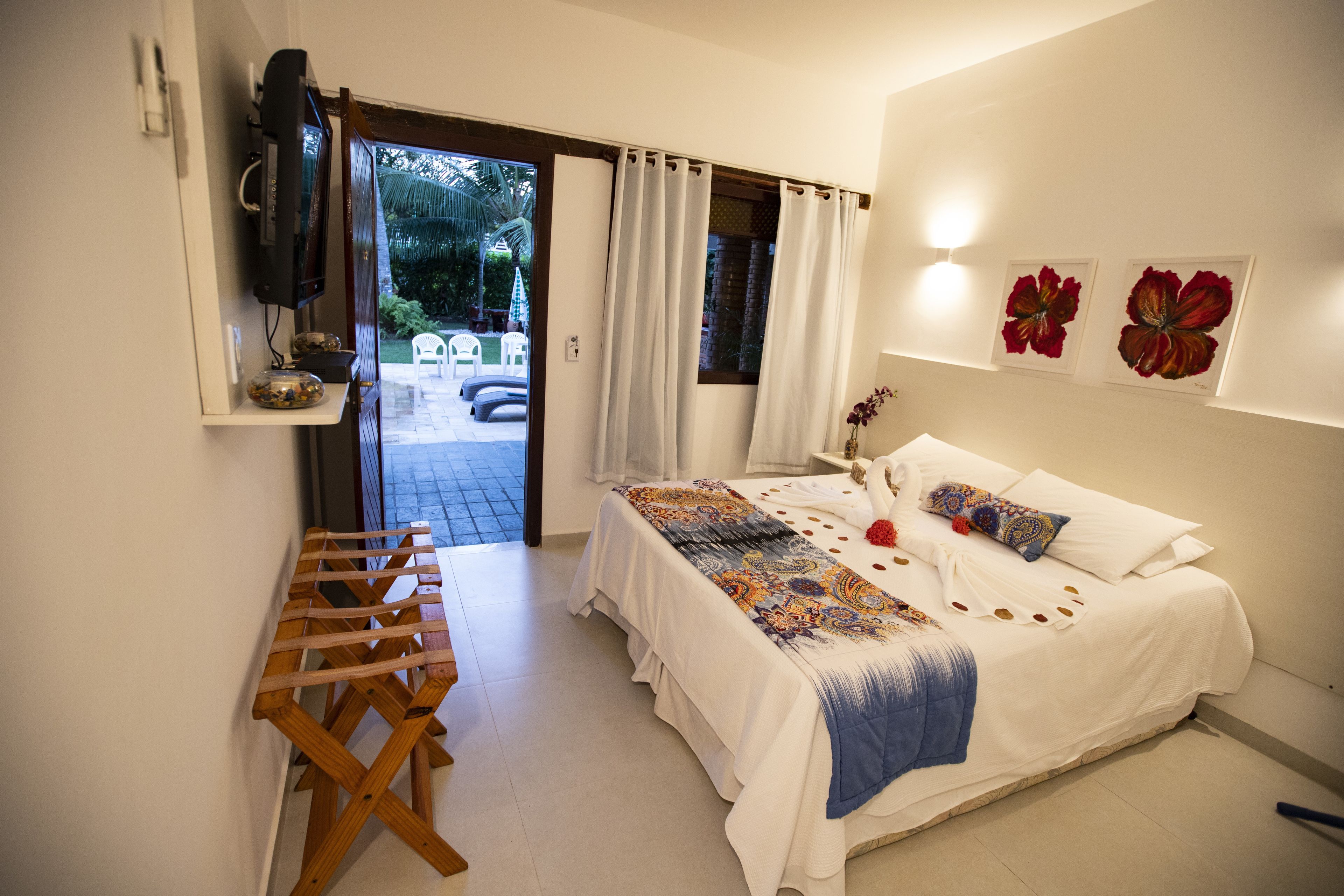 Un dormitorio con cama, una mesa de madera y un televisor en la pared.