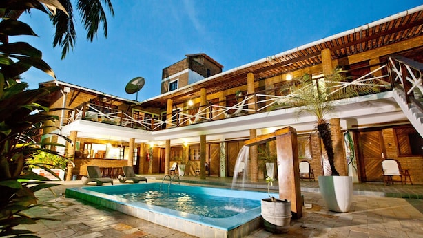 A pool area with a hot tub, lounge chairs, and a staircase leading to an upper level. - Pousada Lua Cheia (Marechal Deodoro)