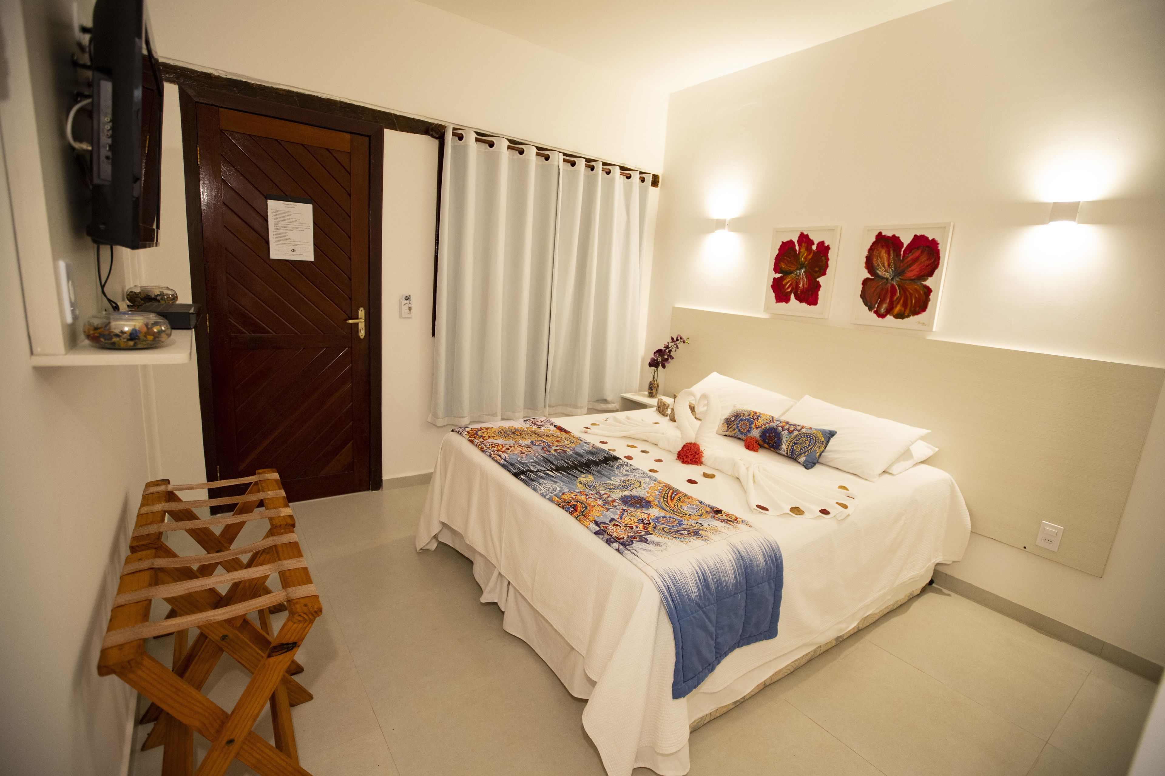 A bedroom with a bed, a wooden table, a TV, and a door.