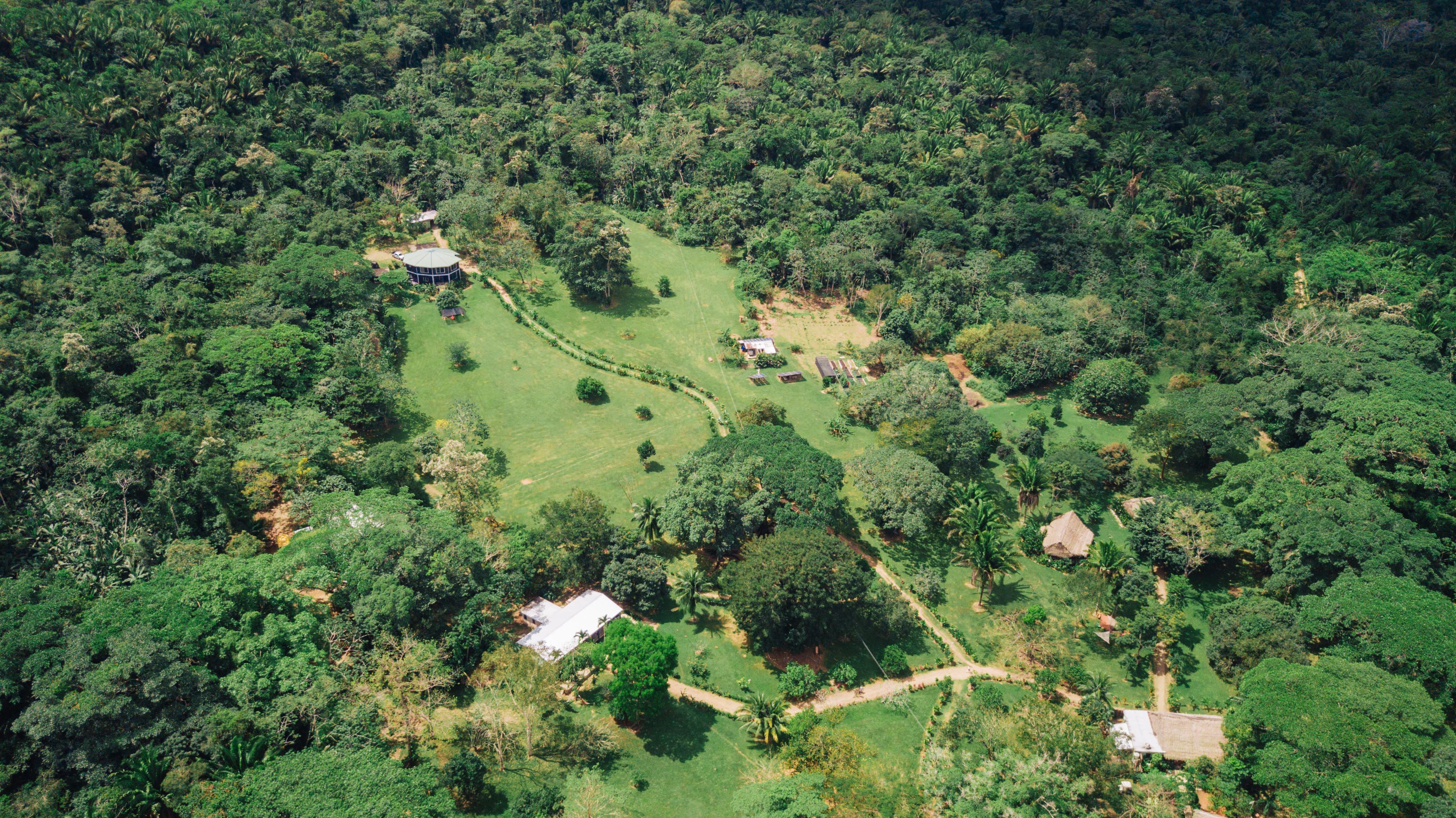 Vista aérea de una propiedad rural con varias construcciones, rodeada de un bosque denso.