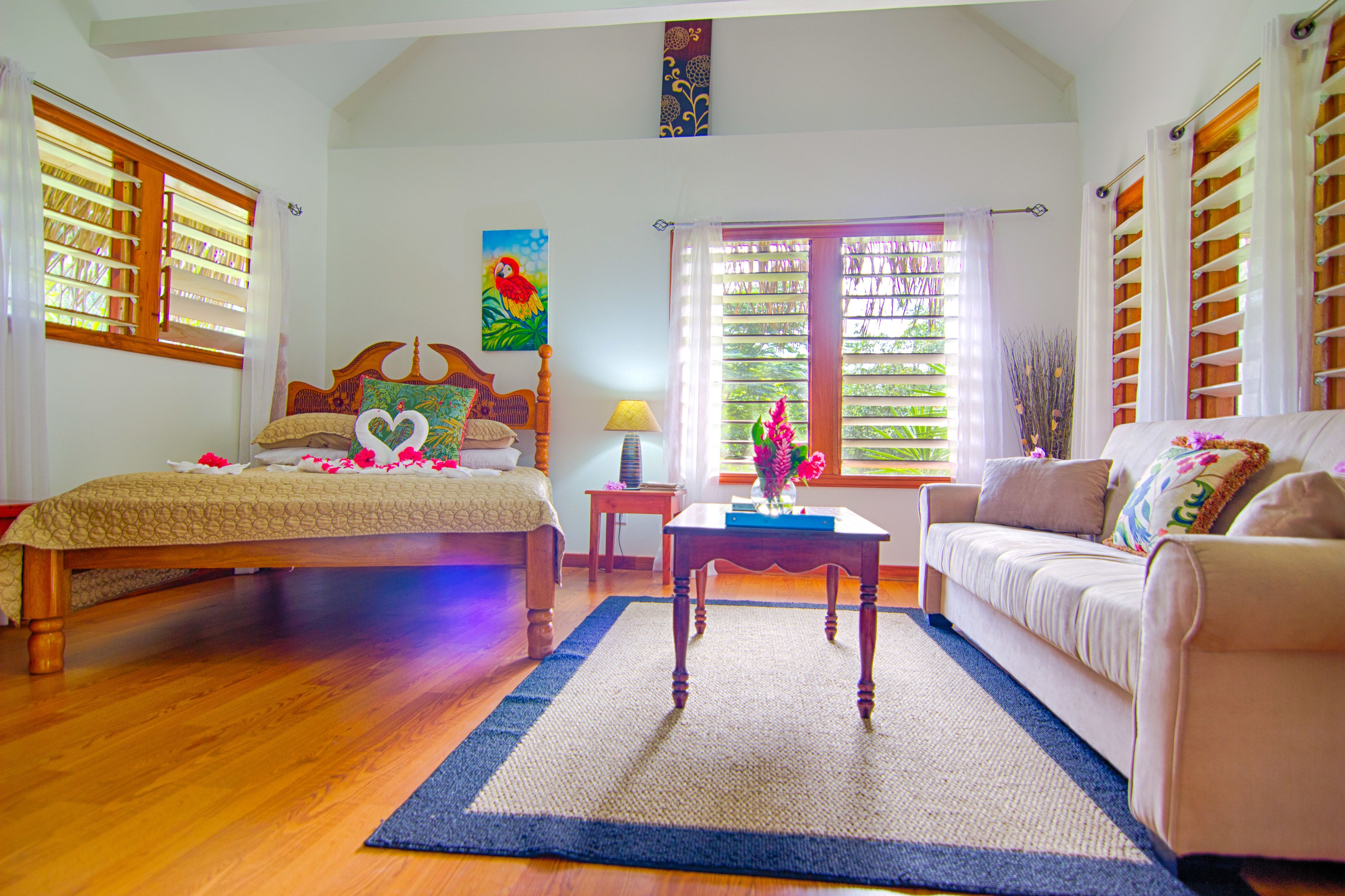 A bedroom with a bed, a sofa, a nightstand, and a window with blinds.