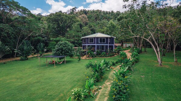 A two-story house with a garden pathway leading to it, surrounded by lush greenery. - Bocawina Rainforest Resort & Adventures (Hopkins)