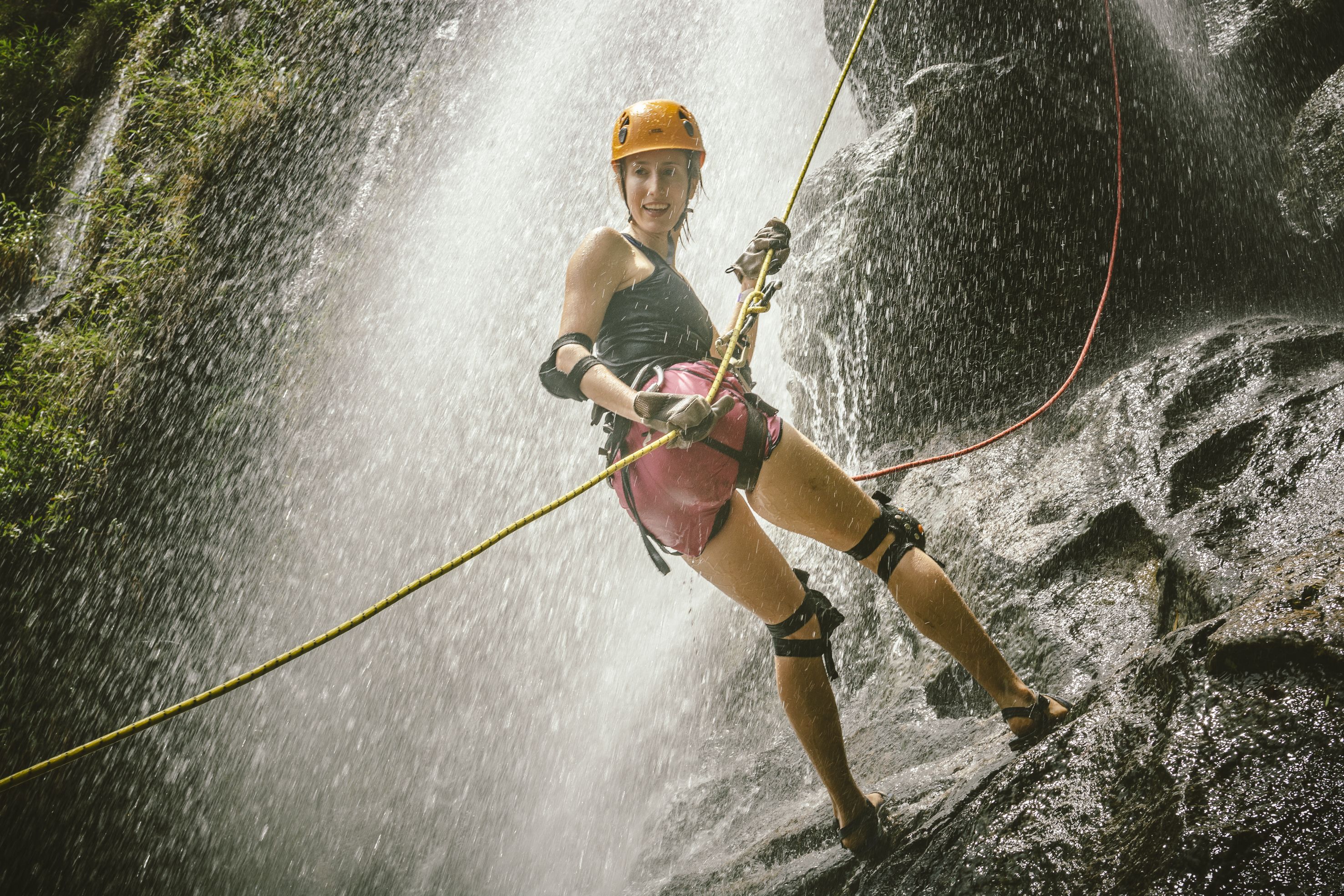 Una persona fent rappel per una cascada rocosa.