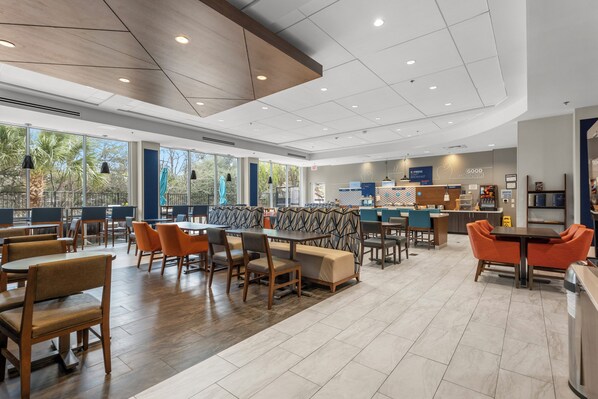 A spacious dining area with high ceilings, large windows, and a variety of seating options including tables and booths.