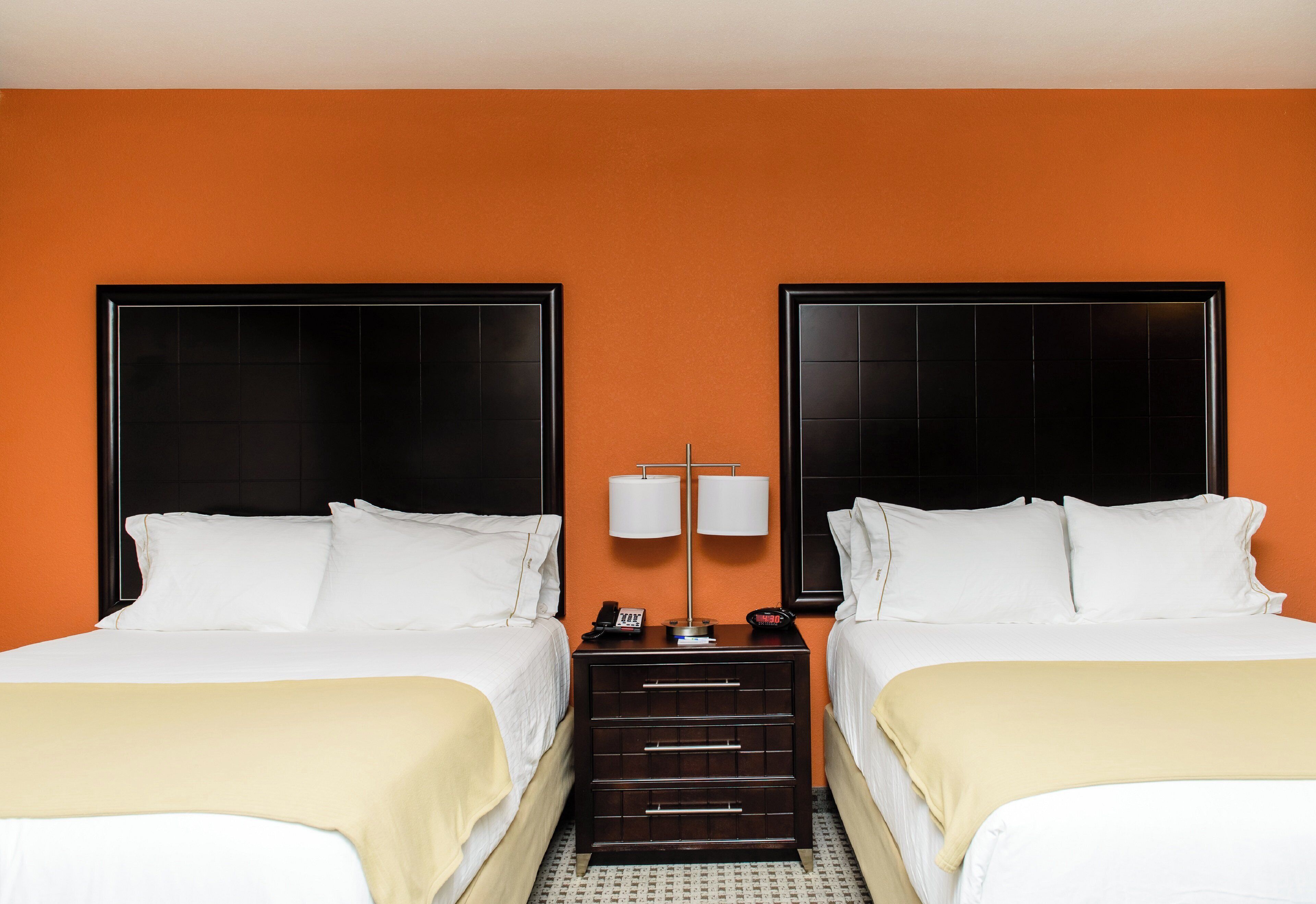 Una habitación de hotel con dos camas, una mesita de noche con lámpara y un teléfono.