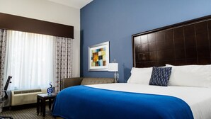 Een hotelkamer met een groot bed, een bureau, een stoel en een raam met gordijnen.
