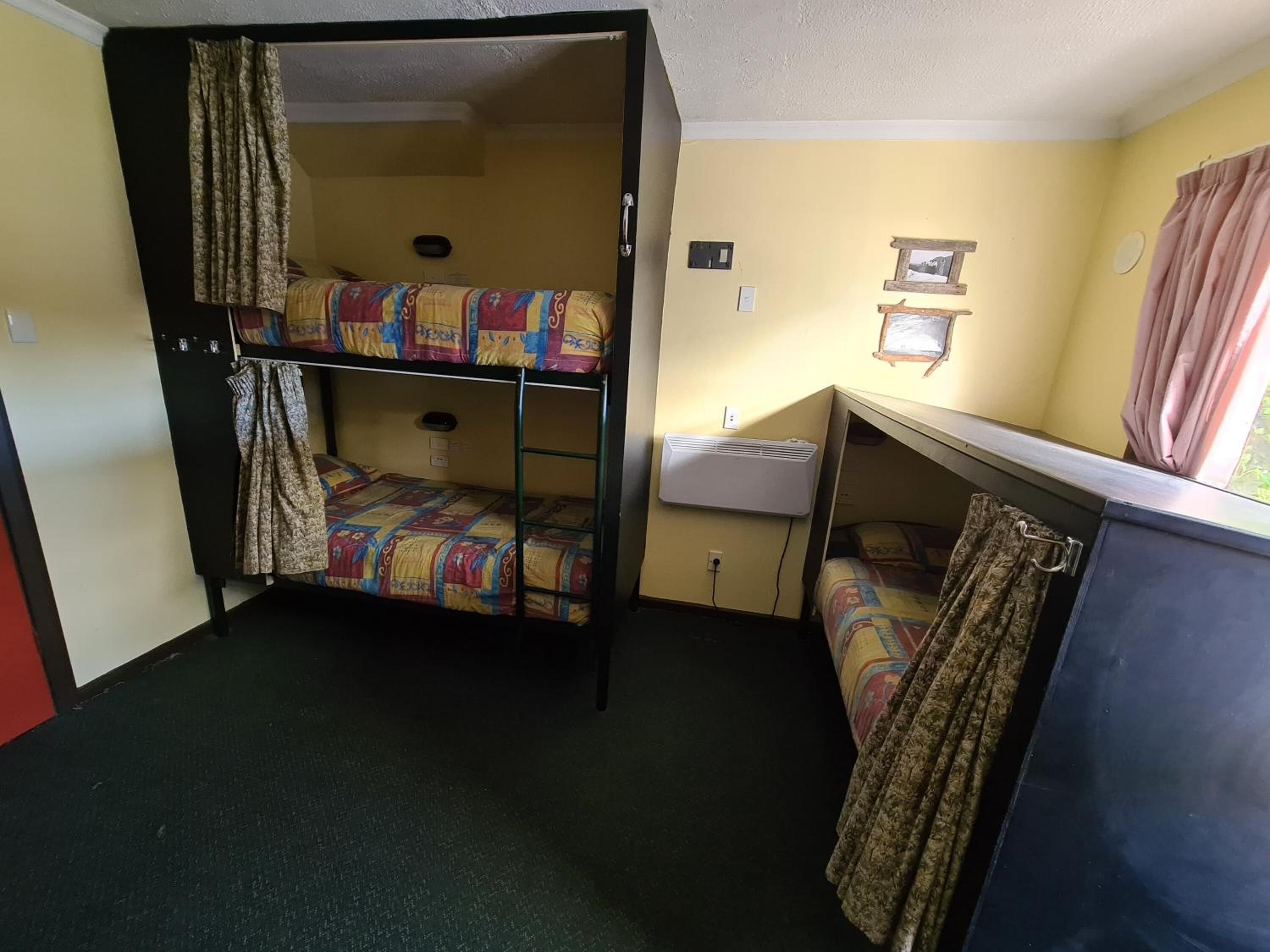 Een slaapkamer met een stapelbed, bureau en raam.