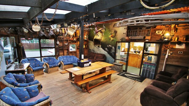 A rustic interior with wicker furniture, a wooden table, and a mural.