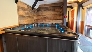 A hot tub with blue lights, wooden walls, and a ceiling with exposed beams.