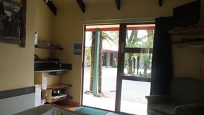 A room with a bed, a chair, a sink, and a door leading outside.