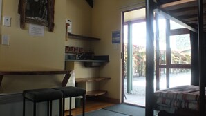 A room with a bed, a bench, a sink, and a door leading outside.