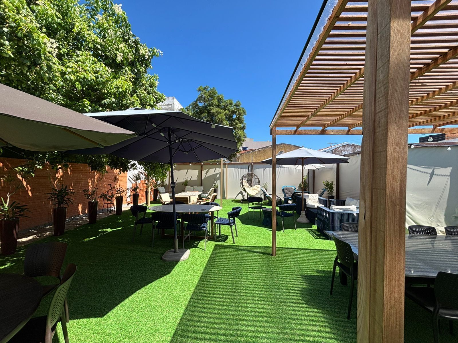 A patio area with artificial grass, outdoor furniture, and umbrellas.