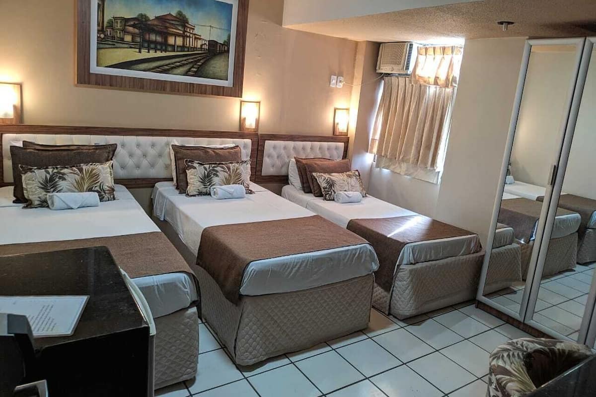 A hotel room with two beds, a desk, and a large mirror.