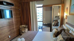 A hotel room with a bed, a TV mounted on the wall, a desk, and a chair.