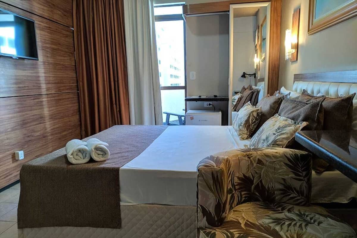 A hotel room with a bed, a sofa, a TV, and a desk.
