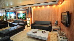 A modern lounge area with a sofa, a coffee table, and a TV mounted on the wall.