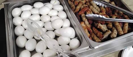 A buffet with two trays, one containing boiled eggs and the other containing sausages.