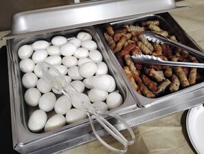 A buffet with two trays, one containing boiled eggs and the other containing sausages.