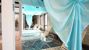 Une pièce avec un espace piscine, comprenant des chaises longues et une table en verre.
