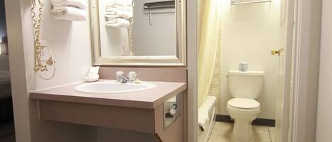 Un baño con lavamanos, espejo, toallero y retrete.