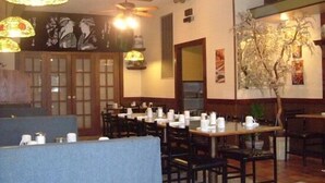 L’intérieur d’un restaurant, avec des tables et des chaises en bois, ainsi que des lampes décoratives en forme de fleurs suspendues au plafond.