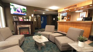 Un espace d’accueil d’hôtel comprenant un téléviseur, des canapés, une cheminée et un comptoir de réception.