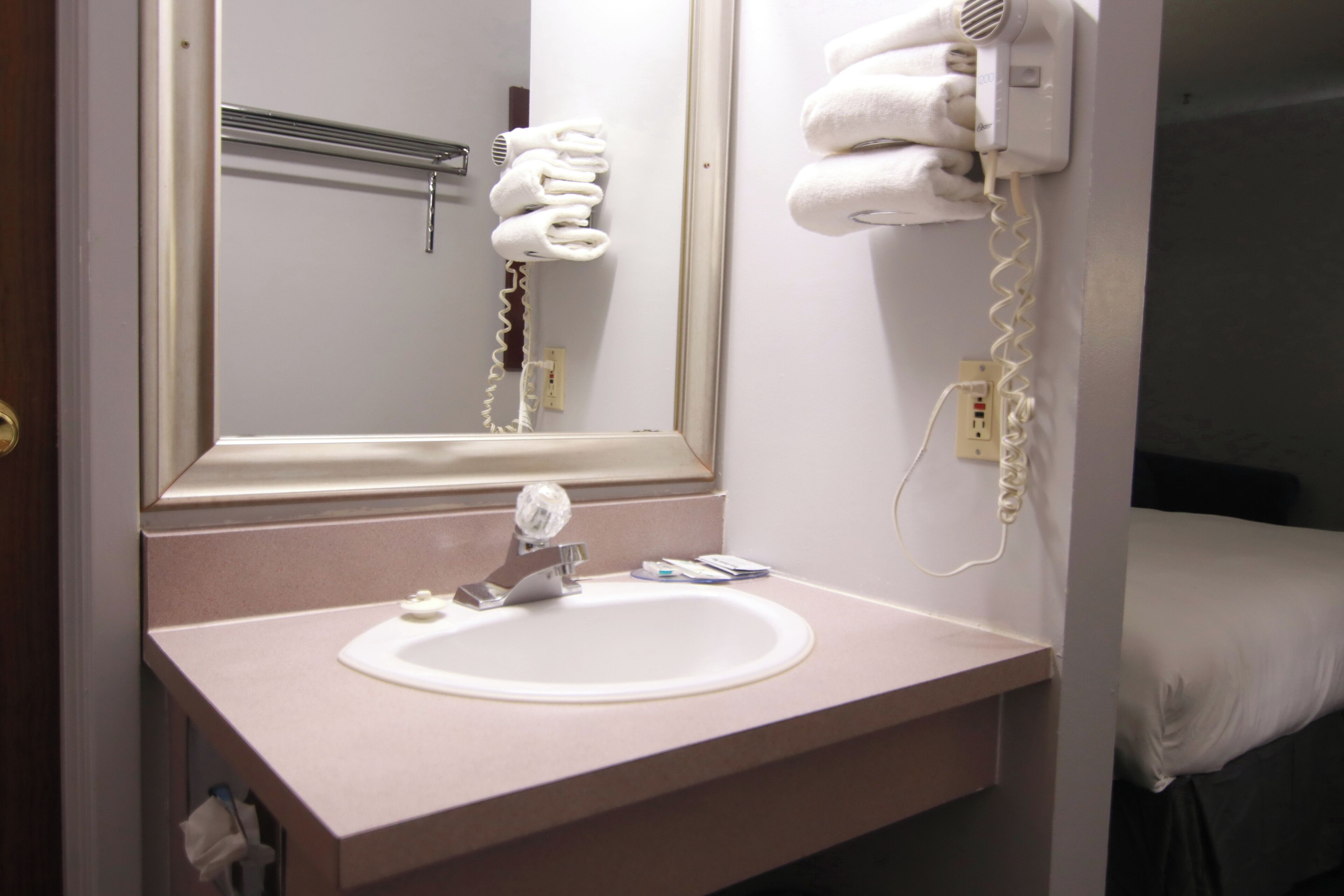 A bathroom with a sink, mirror, towel rack, and hairdryer.