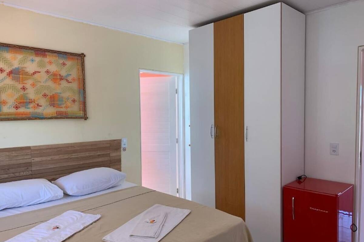 Una habitación de hotel con una cama, un armario y un aparador rojo.