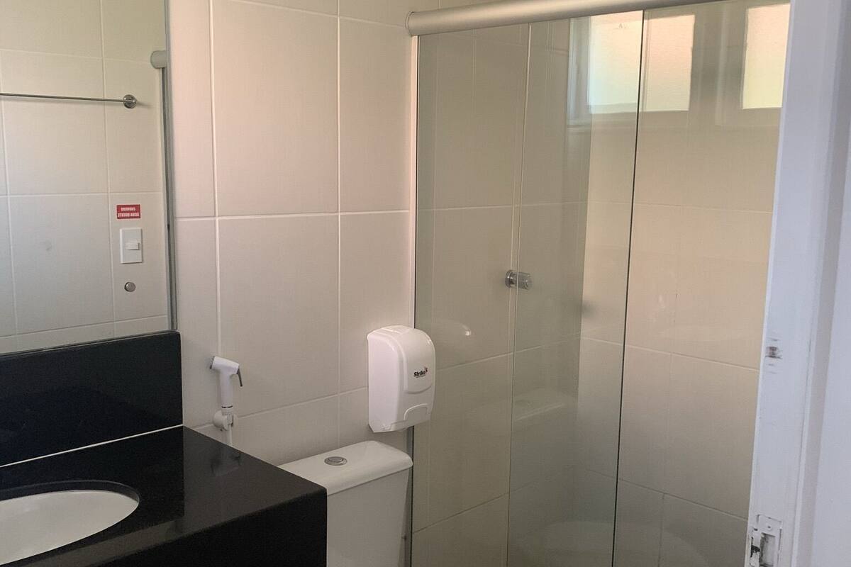Un baño con un lavabo negro, un inodoro blanco y una cabina de ducha de vidrio.